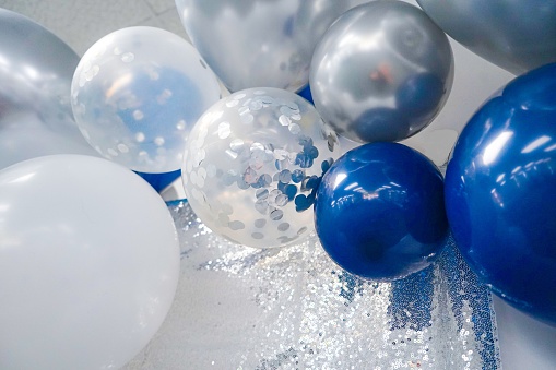 White, Silver, Confetti, and Royal Blue Balloons against a silver sequins and white background.