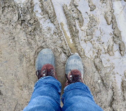 A close view of the pair of boots in the muddy ground.