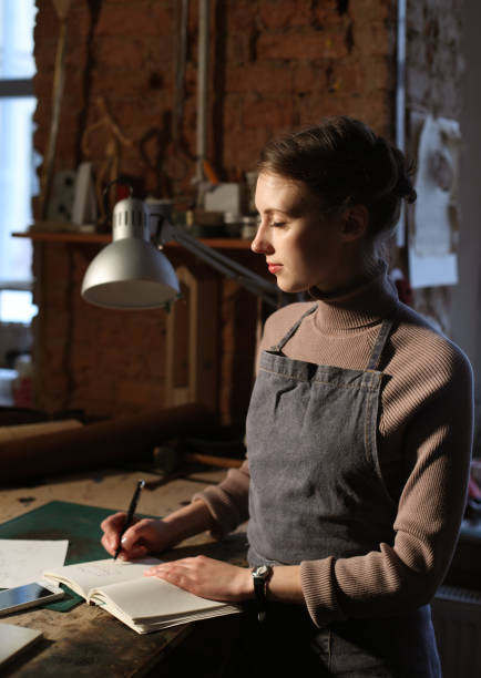 istock young woman writes to notebook in sewing workshop, handmade concept 1500155824