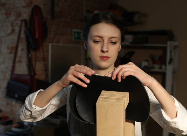 若いブルネットの女性は、バッグ作りのスタジオで働き、細部を切り取ります - tools for construction ストックフォトと画像