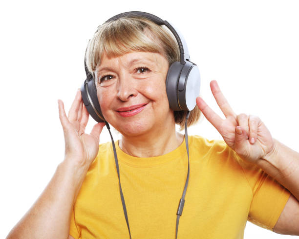 Lifestyle, tehnology and people concept: Funny old lady listening music and showing thumbs up. stock photo