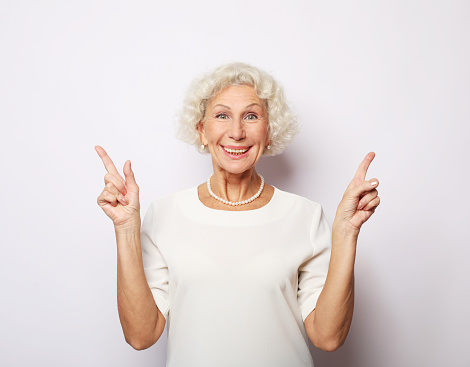 Lifestyle, emotion and old people concept: good mood happy smiling positive old woman show v-sign isolated over white background