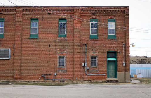 A brown brick wall with a green door in Pacific, Missouri
