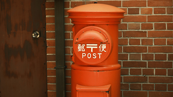 Red mailbox placed in front of a brick house