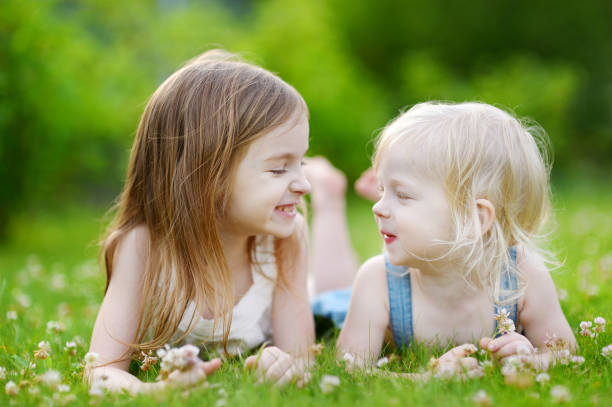 istock Two cute little sisters laying in the grass 1500175553