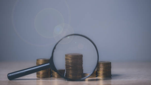 istock Growing stacks of coins with magnifying glass. 1500176495
