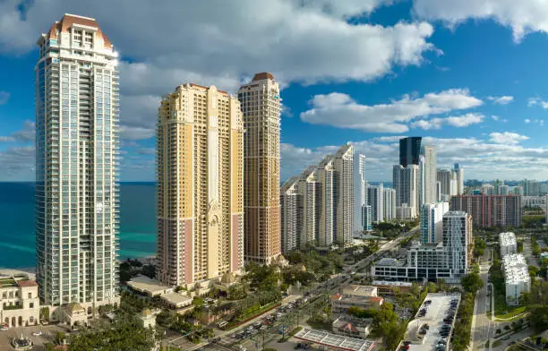 Photo of Expensive highrise hotels and condos on Atlantic ocean shore in Sunny Isles Beach city and busy street traffic. American tourism infrastructure in southern Florida