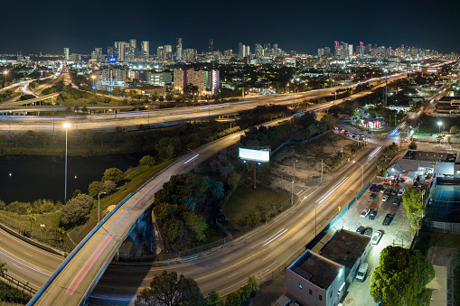 Aerial view of american freeway intersection at night with fast driving cars and trucks in Miami, Florida. View from above of USA transportation infrastructure.