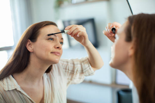 istock Young woman putting on makeup while looking in a mirror at home 1500186220