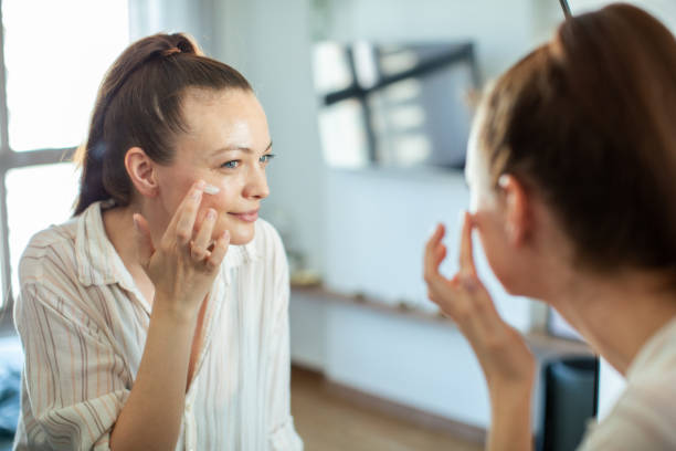 istock Young woman putting on makeup while looking in a mirror at home 1500186292