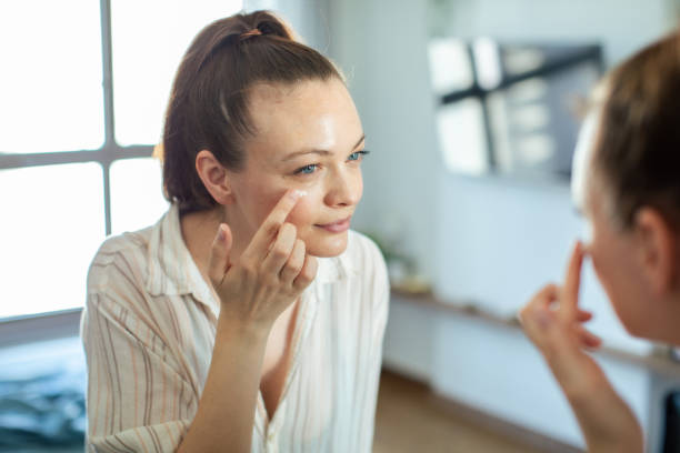 istock Young woman putting on makeup while looking in a mirror at home 1500186307