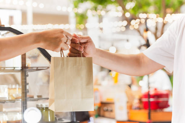 Waitress giving eco friendly paper bag to customer take out. Waitress giving eco friendly paper bag to customer take out curbsidepickup stock pictures, royalty-free photos & images