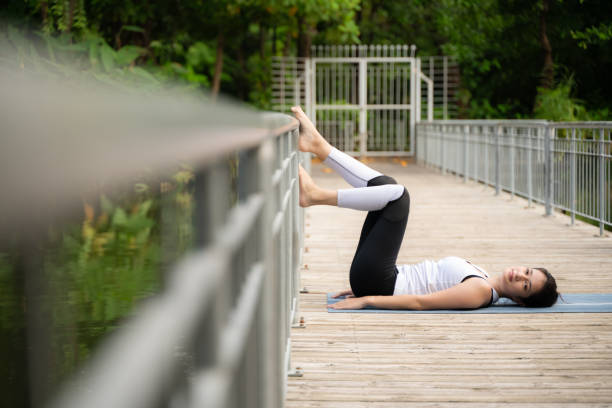 Young female on a wooden bridge in the park with healthy yoga activities Young female on a wooden bridge in the park with healthy yoga activities women lying down grass wood stock pictures, royalty-free photos & images