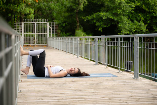 Young female on a wooden bridge in the park with healthy yoga activities Young female on a wooden bridge in the park with healthy yoga activities women lying down grass wood stock pictures, royalty-free photos & images