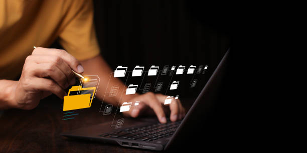 istock Document Management System (DMS) being setup by IT consultant working on laptop computer in office with document directory. Software for archiving, searching and managing corporate file information 1500208483