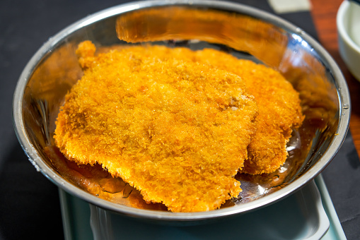 Tasty cracklings in frying pan isolated on white. Cooked pork lard