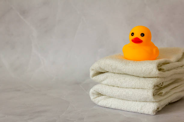 A yellow rubber duck for bathing on a stack of clean white towels