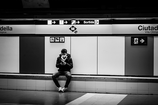 Barcelona, Spain - December 12, 2022: A young man sits waiting for the arrival of the metro in one of the city's stations.
