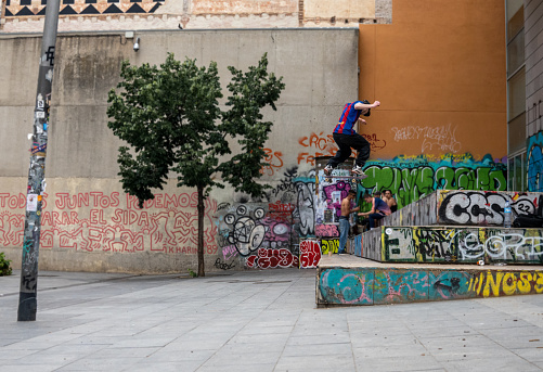 Barcelona, Spain - May 26, 2023: Skateboarder jumps down famous stair set at the  Museum of Contemporary Art of Barcelona.
