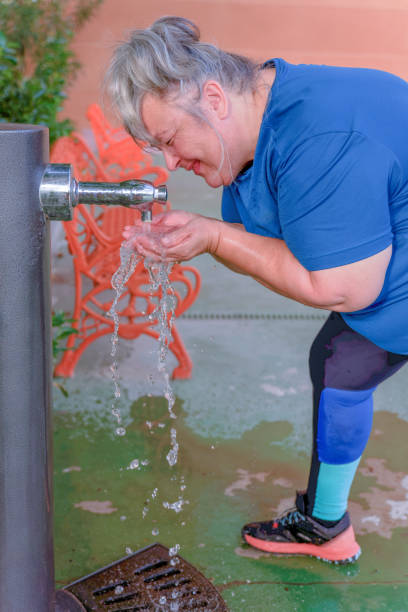 istock elderly woman drinking water from a fountain after exercise 1500223009