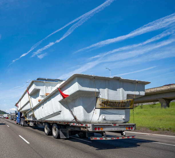 istock Blue big rig powerful semi truck transporting oversize cargo on flat bed semi trailer with oversize load sign on the back running on the multiline highway road 1500224643
