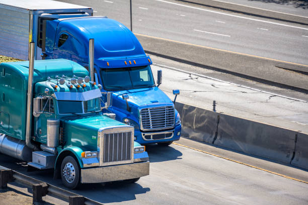 istock Two big rig semi trucks classic and new styles with flat bed and refrigerator semi trailers running on the multiline highway road 1500225056