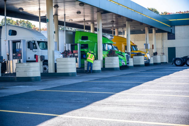 Pro industrial big rigs semi trucks with semi trailers refuel tanks stand at truck stop gas station stock photo