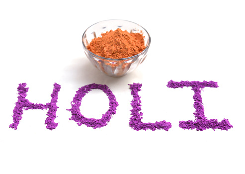 Holi greetings concept and colored powder (Gulal) on white background.