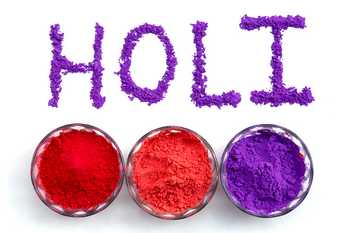 Holi greetings concept and colored powder (Gulal) on white background. Holi is a popular and significant Hindu festival celebrated as the Festival of Colours, Love and Spring. It celebrates the eternal and divine love of the god Radha and Krishna.