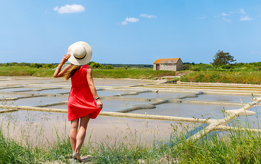 Woman tourist with red dress enjoying salt marsh in Guerande,  Saline- Loire Atlantic,  Pays de la Loire in France