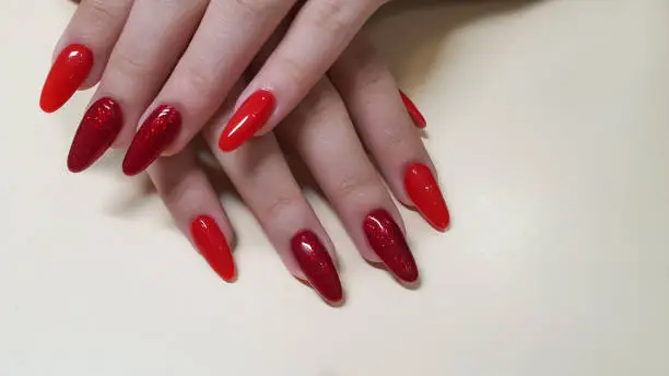 Manicure and nail extension with acrylic and gel. The design was made with red gel polishes in a beauty salon. copy space