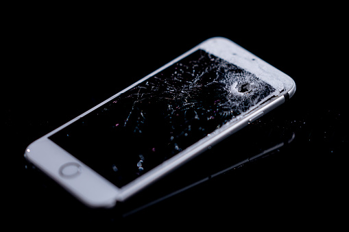 Close-up of damaged mobile phone against black background.