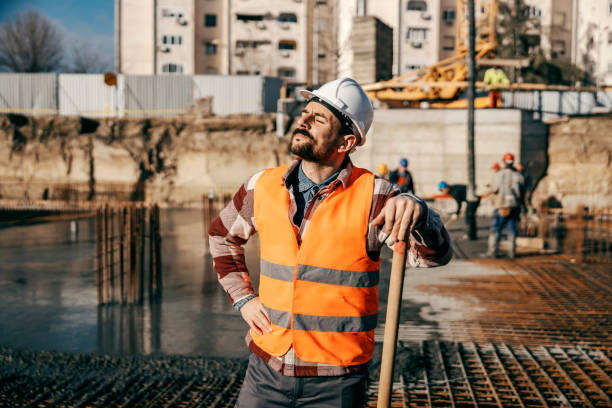 istock A hardworking builder is leaning on the shovel and taking a break from hard work while other builders concreting building foundation on site in blurry background. 1500235769