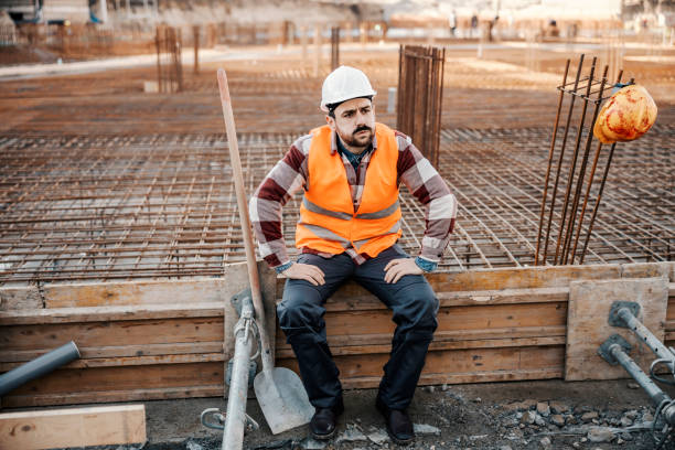 istock A tired site worker is sitting on a building foundation and resting from hard work on site. 1500236321