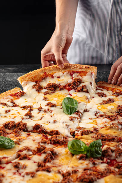 istock Baker taking off a slice of pizza with minced beef 1500237391