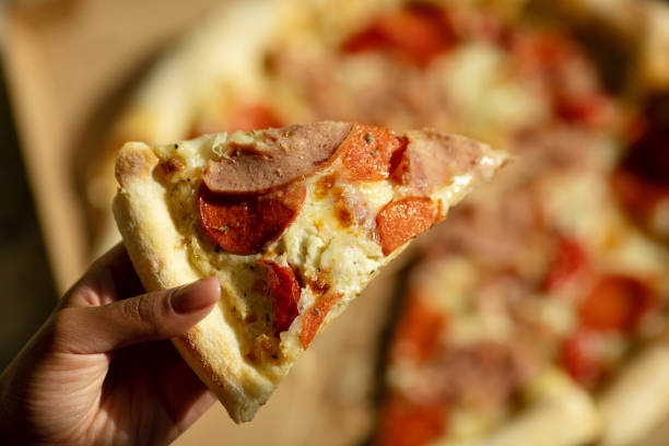 istock Hot pizza slice with melting cheese. Close up Italian pizza with cheese it stick. Selective focus. Blurred background. 1500239421