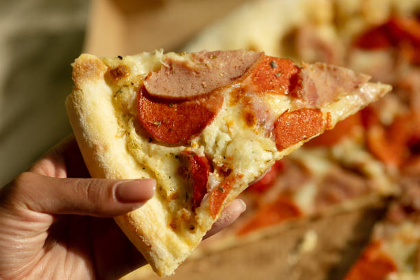 istock Hot pizza slice with melting cheese. Close up Italian pizza with cheese it stick. Selective focus. Blurred background. 1500239439