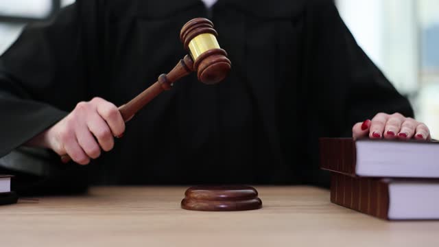 Judge in robe knocks wooden gavel in courtroom