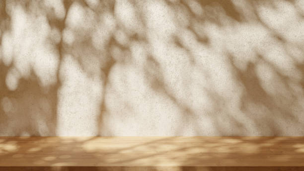 istock Empty table on light beige texture wall background. Leaves shadow on the wall. Mock up for presentation, branding products, cosmetics food or jewellery. 1500243524