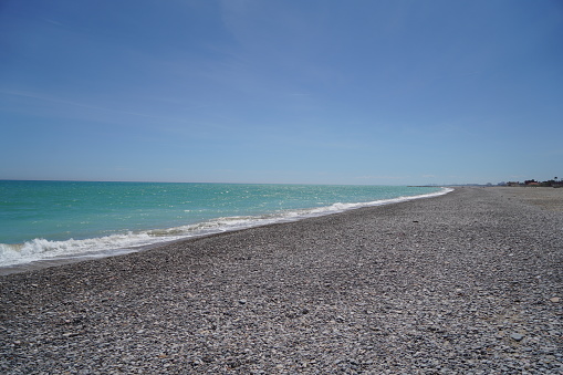 waves on mediterranean sea with pebble beach and green water