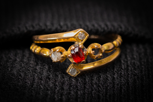 Antique ladies engagement or wedding ring with a four white diamond cluster and a red ruby type stone in the centre. One stone is missing and would be a good image for a jewellery repair or similar.