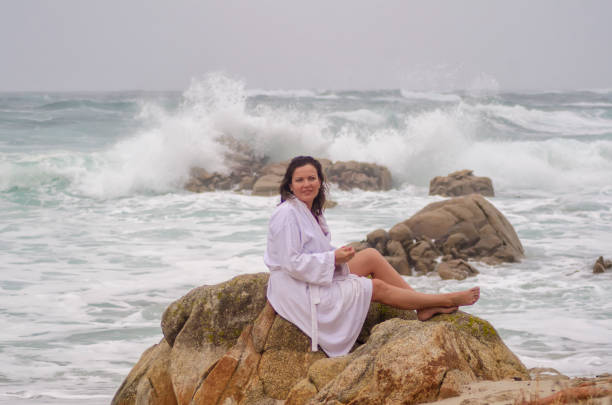 istock woman sitting on the rocks on the beach 1500244700