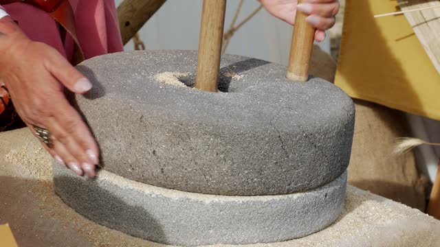hand using a large authentic millstone, medieval utensil for grinding grains
