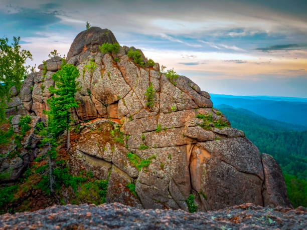 istock Rock overgrown with trees illuminated by the setting sun. Dramatic sky 1500249846