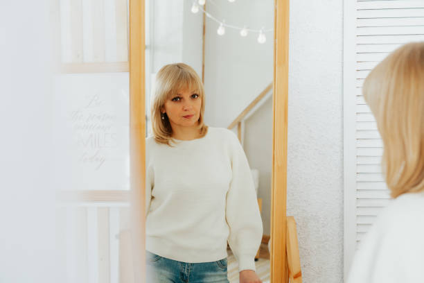 istock woman standing near mirror and looking at reflection 1500251672