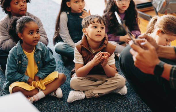 istock Listening comprehension lesson in an elementary class. Kids pay attention to their teacher reading a story 1500254080