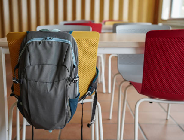 istock a backpack hanging on a chair in a school classroom. Back to school 1500256070