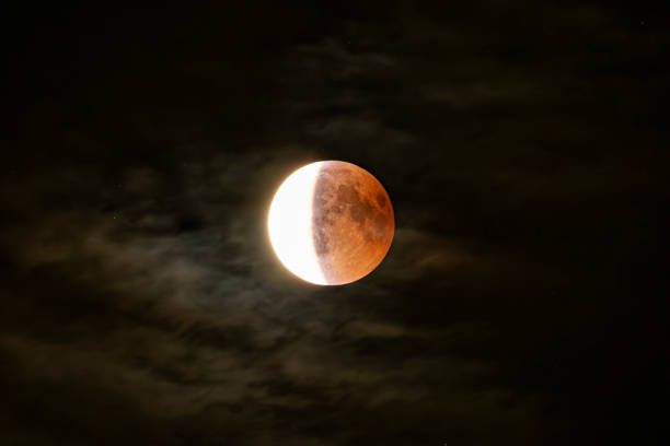 mondfinsternis nahaufnahme in einer bewölkten nacht - lunar eclipse stock-fotos und bilder