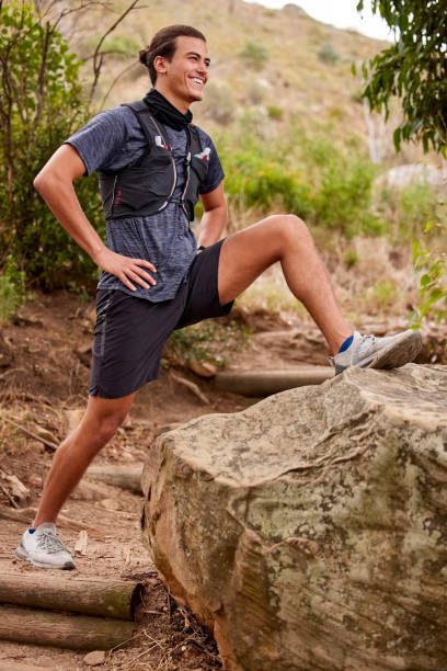 Stretching, fitness and man in forest for running, training or outdoor exercise goals, challenge and sports in nature. Young athlete with muscle warmup for runner cardio workout in woods or mountains estiramientos, fitness y hombre en el bosque para correr, entrenar o objetivos de ejercicio al aire libre, desafío y deportes en la naturaleza. atleta joven con calentamiento muscular para el entrenamiento cardiovascular del corredor en bosques o montaña