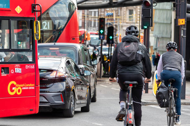 London, England - Jun 06, 2023: Modern Red bus, black cab and urban cyclists in motion on the busy streets of London.